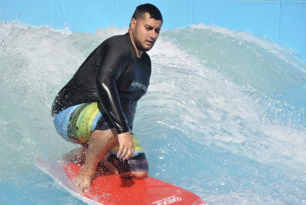 A surfer on a red board at a surf park.